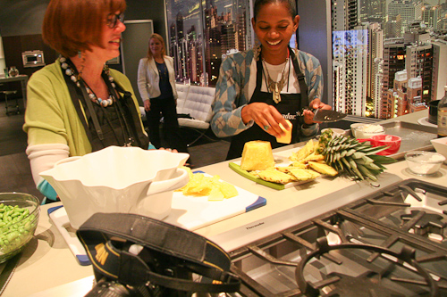 Tabitha chopping pineapple as Susan watches