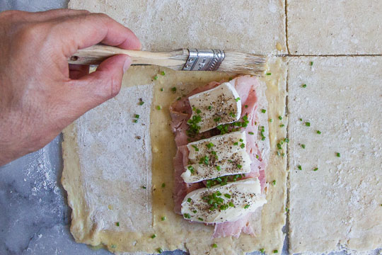 Brush the egg wash around the ham and brie before sealing. Process photo by Irvin Lin of Eat the Love.