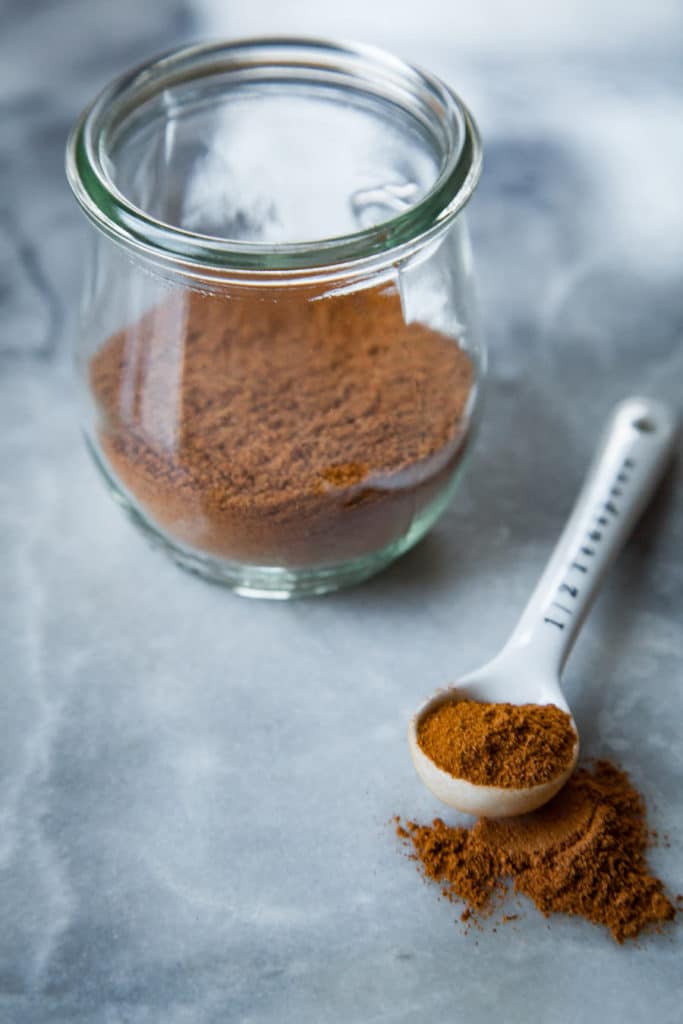 Homemade Pumpkin Spice in a jar with a small measuring spoon with some in it.