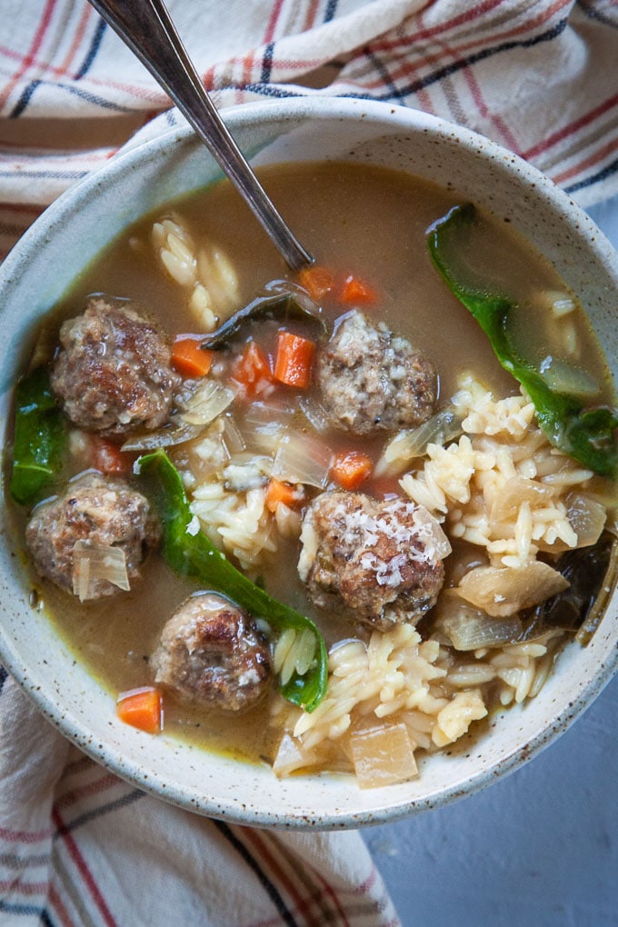 A bowl of Italian Wedding Soup, packed with sausage and beef meatballs, carrots, onions, Swiss chard and orzo pasta.