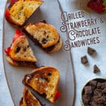 Grilled strawberry and chocolate sandwiches on sourdough crusty bread and a sprinkling of sea salt sitting on a cheeseboard.