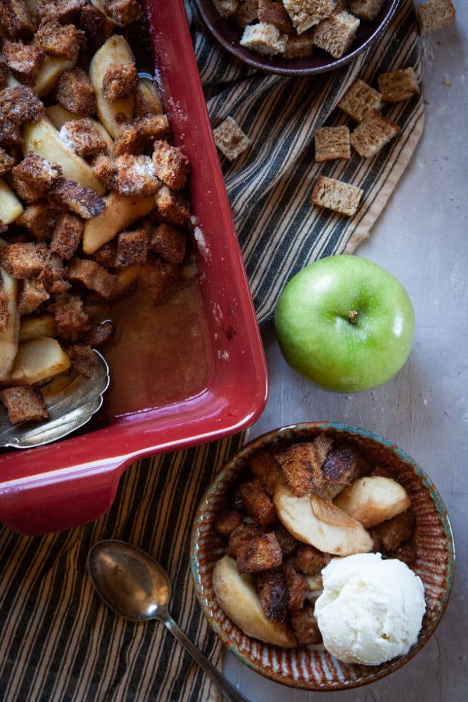 Apple Brown Betty Dessert on a table, served with a scoop of vanilla ice cream.