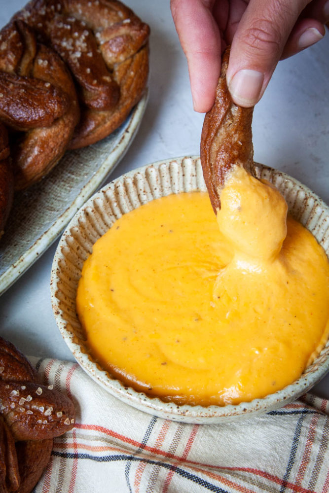 Dipping a piece of soft rye pretzel into a beer cheese dip