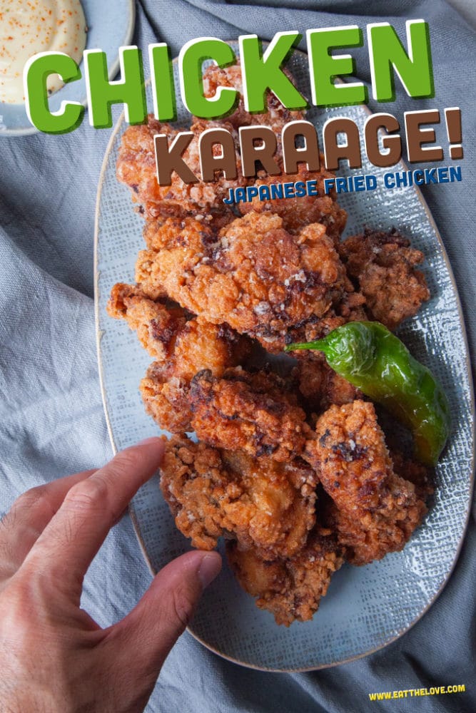 Chicken karaage, japanese fried chicken, piled on a plate with a hand reaching to grab a piece.