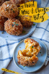 Fried Mac and Cheese Bites on a plate, with one mac and cheese ball open to see the gooey cheese inside.