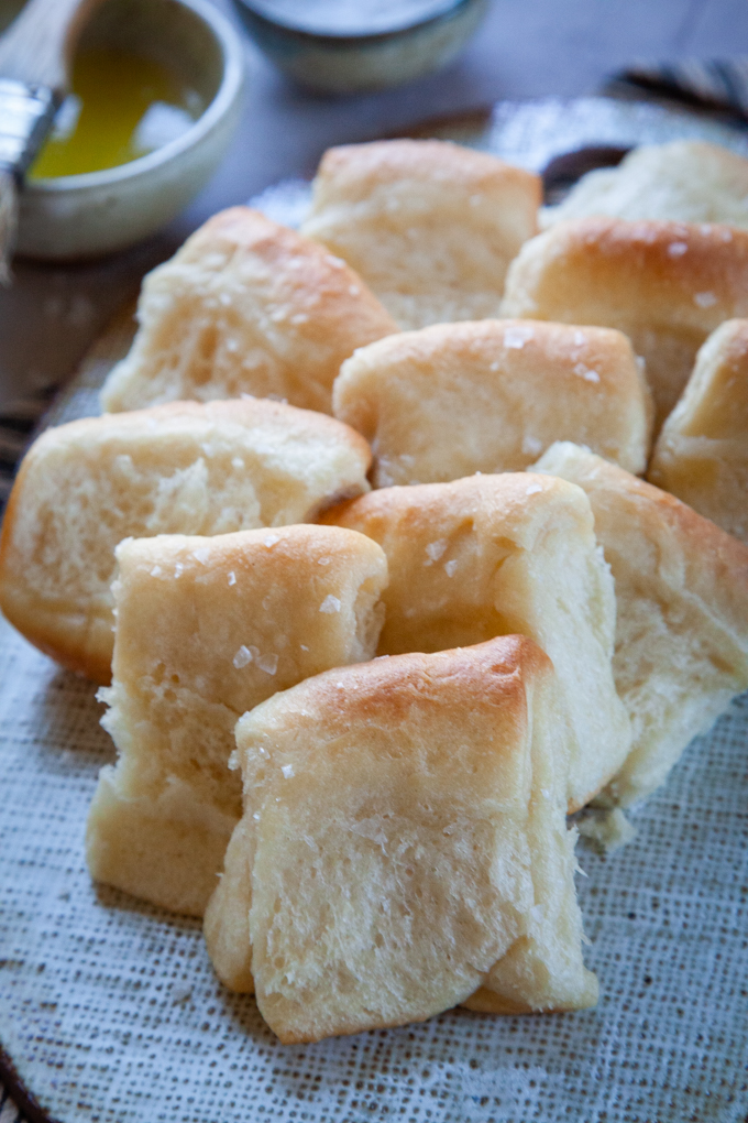 Overnight Parker House Rolls piled up on a serving plate.