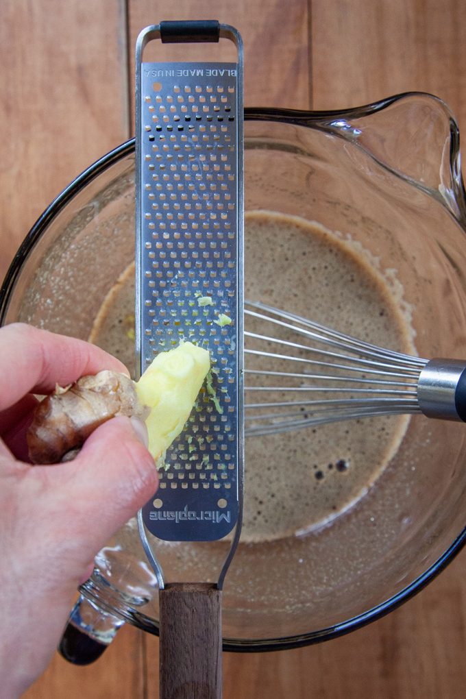 Grating fresh ginger into the batter.
