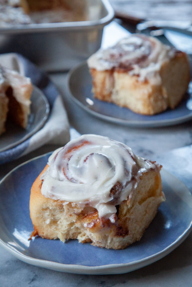 Three eggnog cinnamon rolls on a small blue plates.