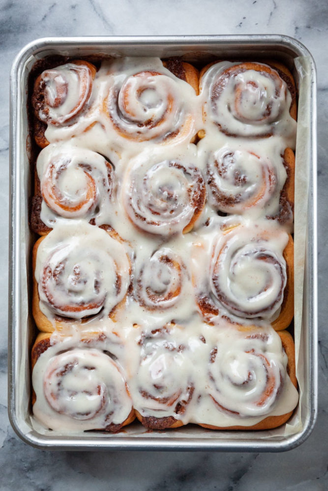 Eggnog Cinnamon Rolls frosted with Bourbon Cream Cheese Frosting in a pan.