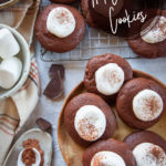 Hot Chocolate Cookies, a cookie that tastes like hot cocoa, sitting on a plate and a wire cooling rack, surrounded by ingredients for the cookie.