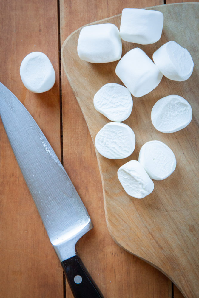 chopped marshmallows on a cutting board with a knife next to it.