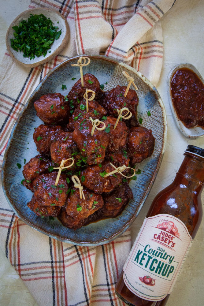 Irish meatballs piled on a plate with ingredients from the recipe surrounding it.