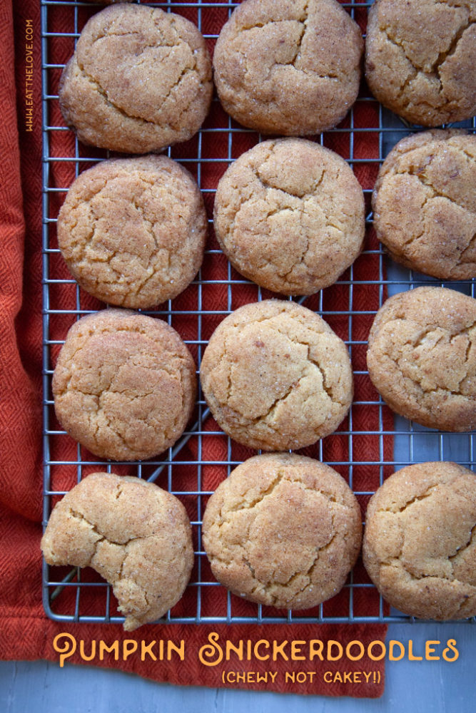 Pumpkin Snickerdoodles cooling on a wire rack, with one cookie that has a bite taken out of it.