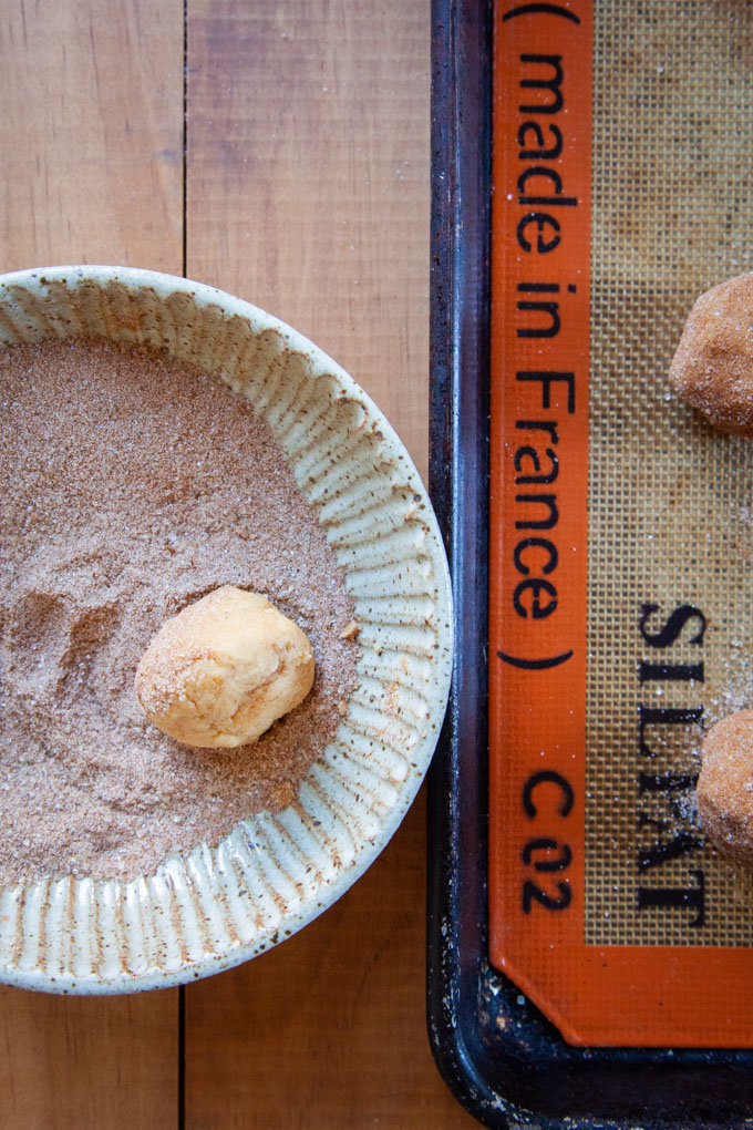 Rolling the pumpkin snickerdoodle cookie dough in the pumpkin-spice sugar mixture.