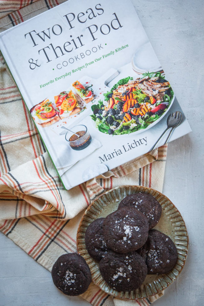 Two Peas and Their Pod Cookbook next to a plate with chocolate salted caramel cookies.