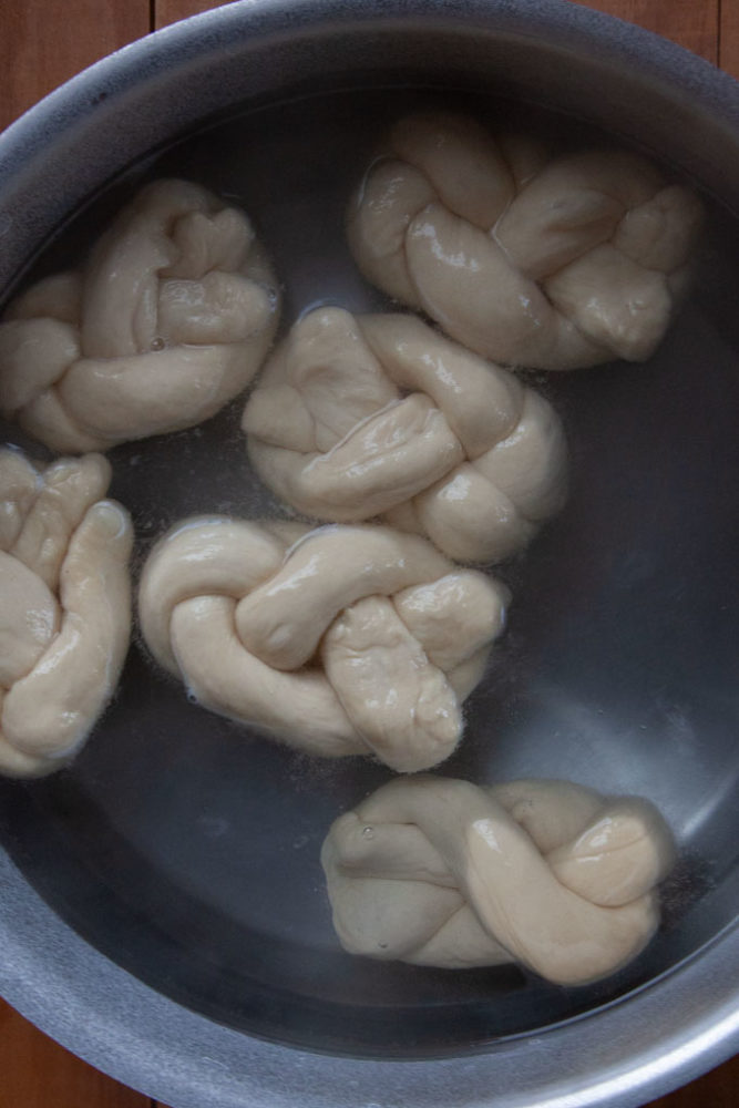 Soft beer pretzel twists boiling in a baking soda solution.