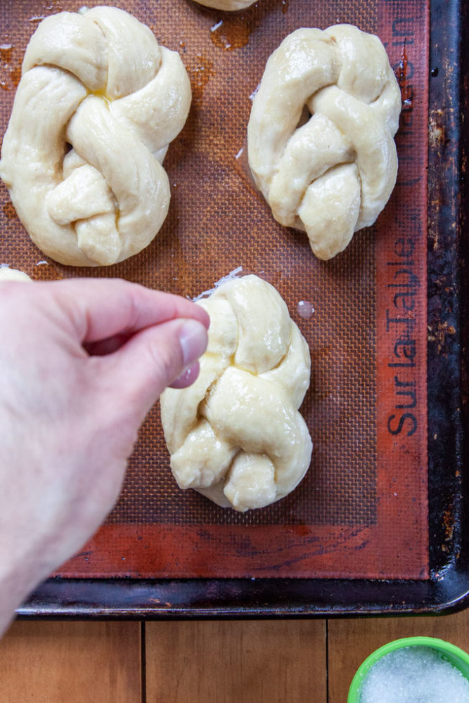 Sprinkling coarse salt over soft beer pretzels before baking.