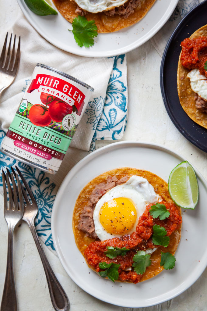 Huevos Rancheros (rancher egg tacos) on plates with a can of Muir Glen petite diced tomatoes next to the plate.