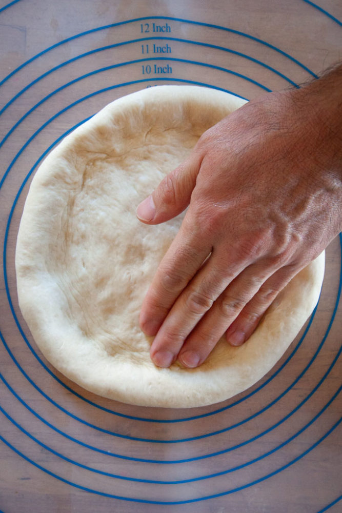 pushing dough into an 8-inch round disk.