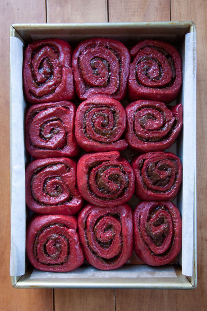 Puffy and risen red velvet cinnamon rolls ready to be baked.
