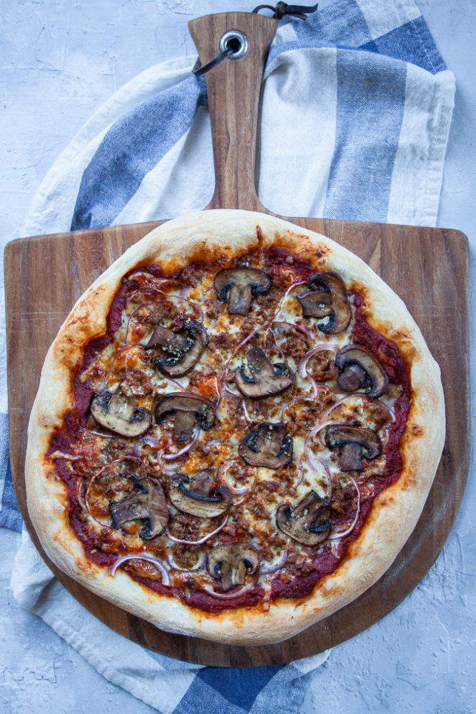 Mushroom pizza on a pizza peel.