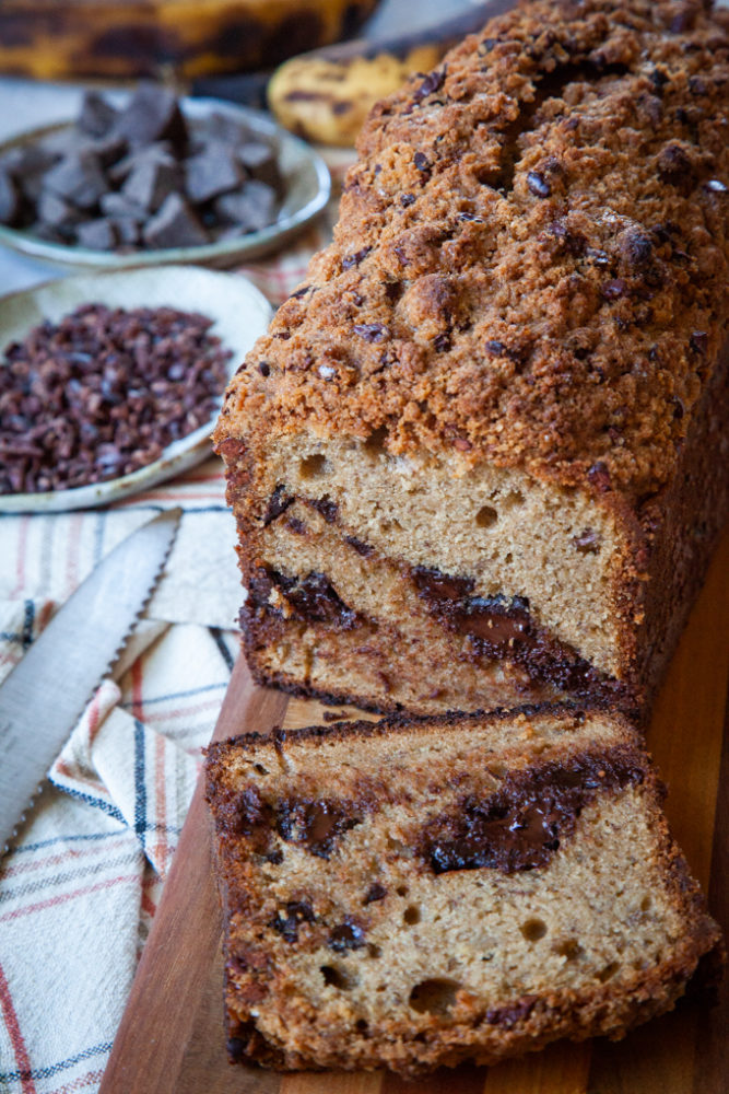 Sourdough Banana Bread loaf with a slice cut off on a cutting board.