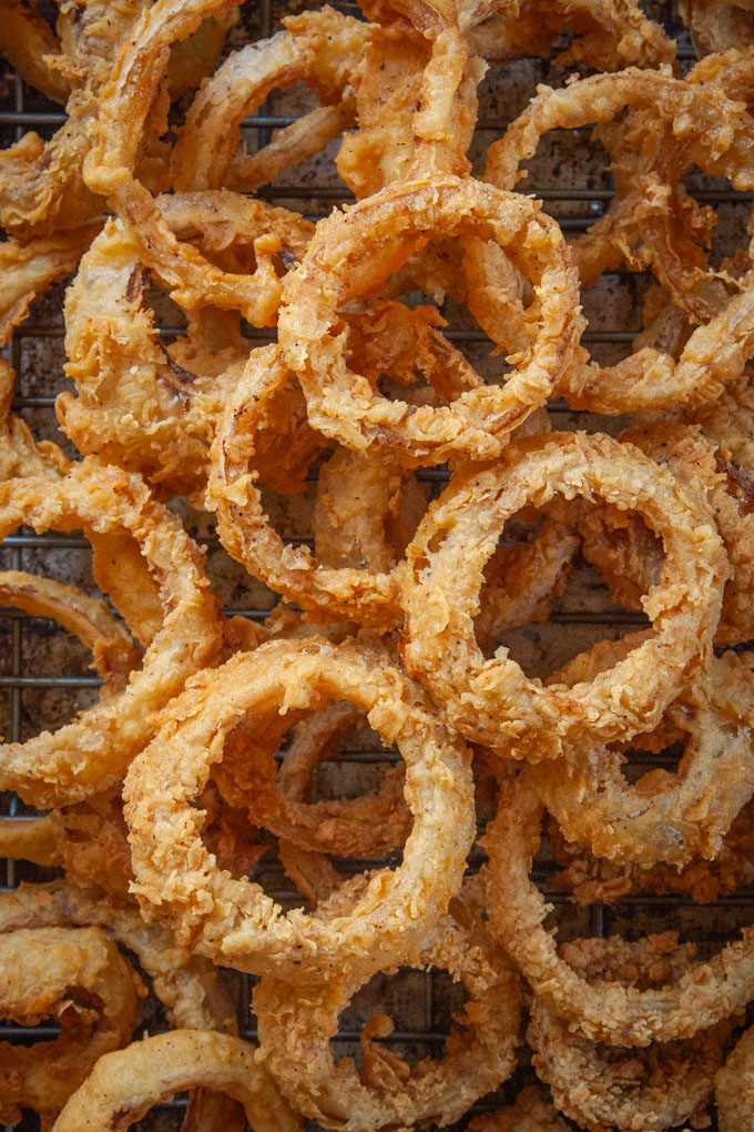 Sourdough onion rings piled up on a baking sheet.