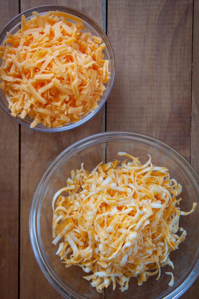 Two bowls of grated cheese.