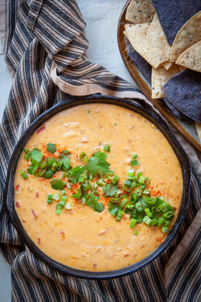 Homemade queso dip in a cast iron skillet next to tortilla chips