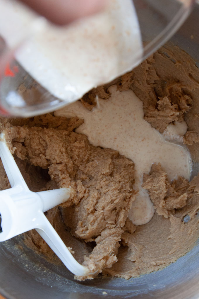 pouring sourdough starter discard into the bowl with the cookie dough.