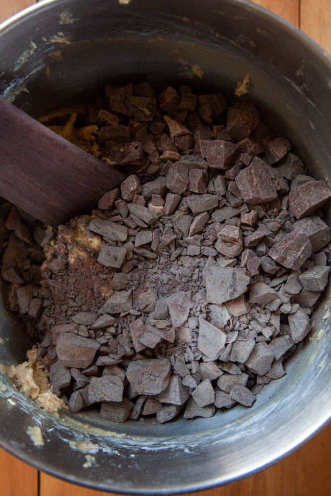 Chopped chocolate being stirred into the dough with a wooden spatula