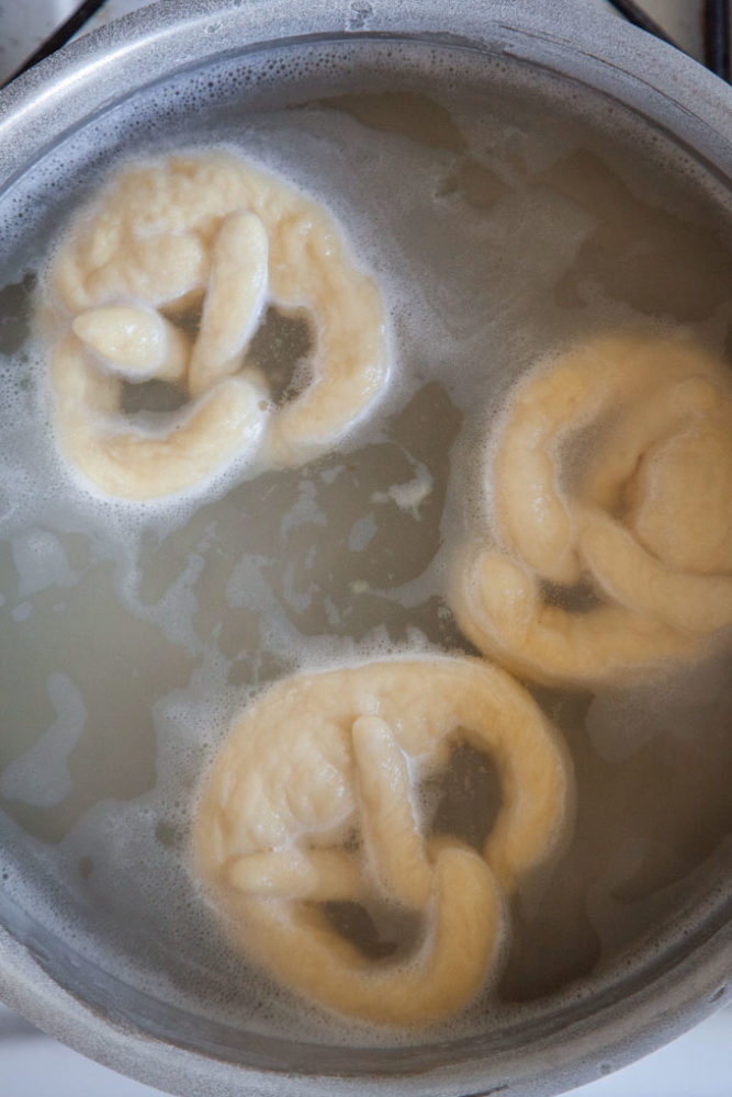 Boiling sourdough pretzels in a baking soda solution.