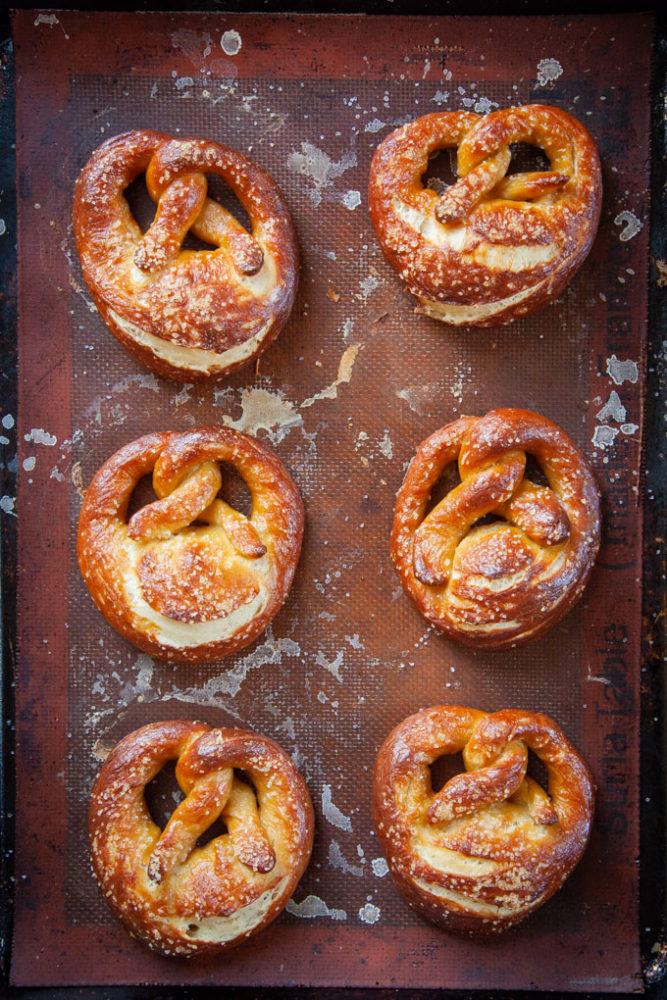 Baked sourdough pretzels on a baking sheet.