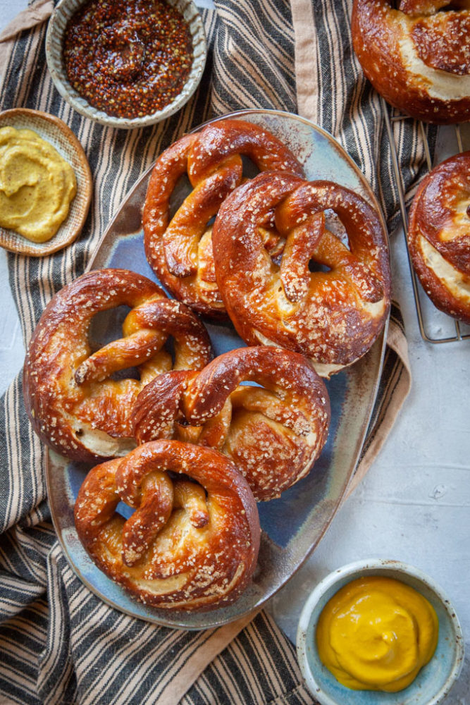 sourdough pretzels on a plate surrounded by small bowls of mustard.
