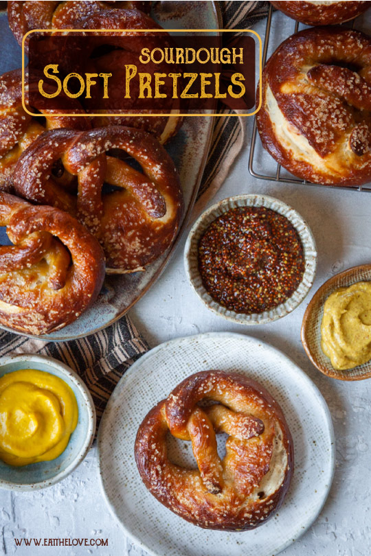 Sourdough pretzels on a plate surrounded by mustards for dipping.