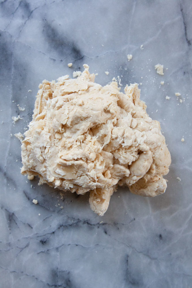 rough sourdough pretzel dough that needs to be kneaded on a marble surface.