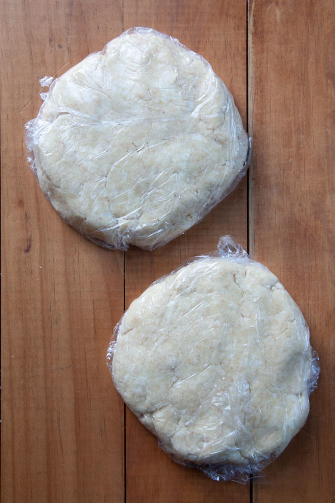 Two rounds of pie crust wrapped in plastic wrap.