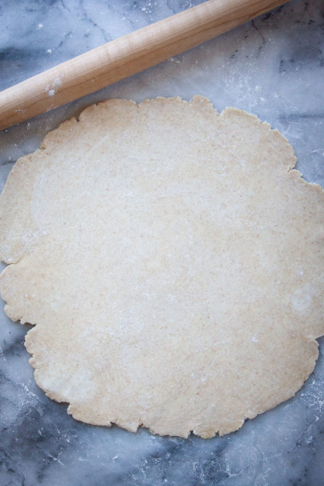 Pie crust rolled out on a marble surface.