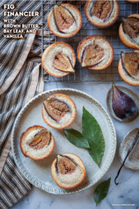 Fig financiers on a plate and wire cooling rack, surrounded by bay leaves, fresh figs and vanilla bean pod.