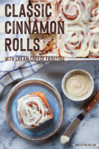 Cinnamon rolls in a pan, with one individual cinnamon roll on a plate next to a small bowl of cream cheese frosting.
