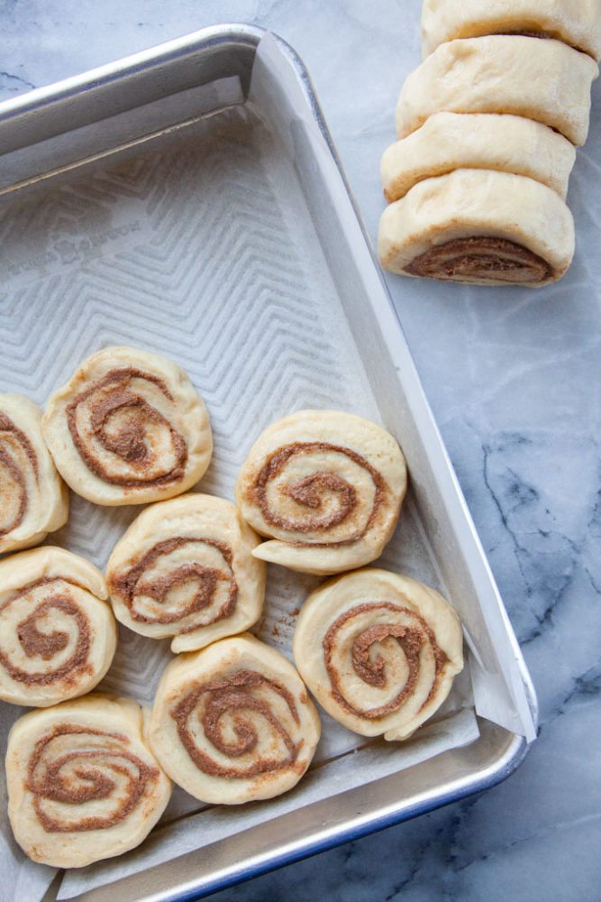 Cinnamon dough cut into disks and placed in a baking pan.