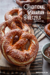 Several Bavarian pretzels on a cutting board.