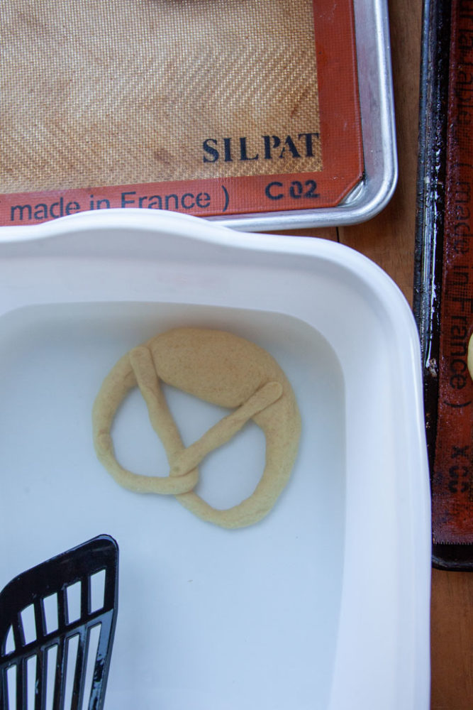 A pretzel being dipped in a lye solution