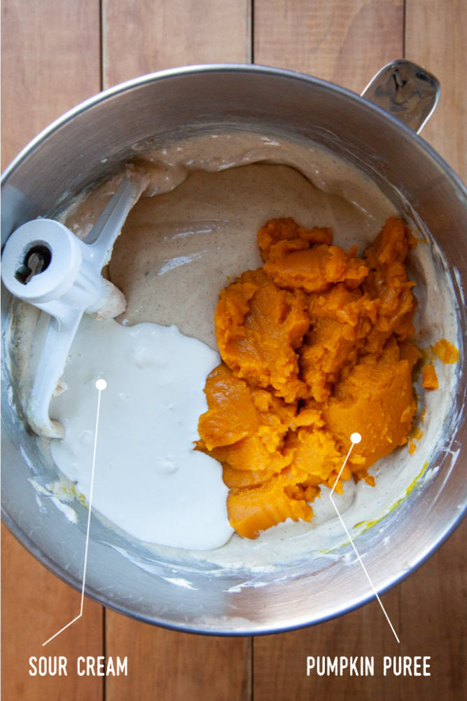 Sour cream and pumpkin puree added to the cheesecake filling in the bowl of stand mixer.