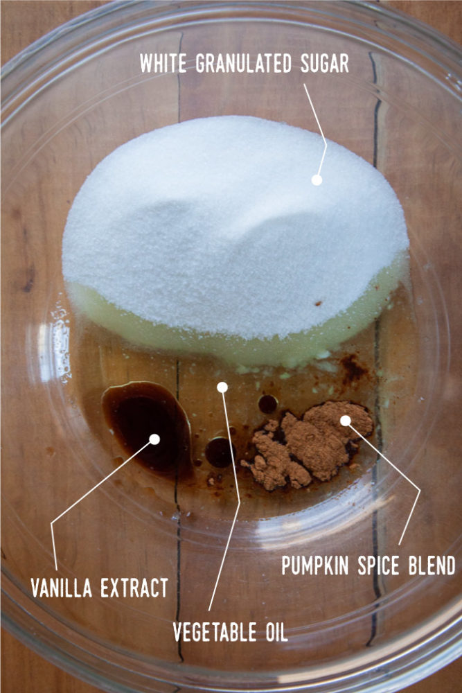 Pumpkin coffee cake batter ingredients in a bowl, including vegetable oil, white sugar, vanilla and pumpkin spice.