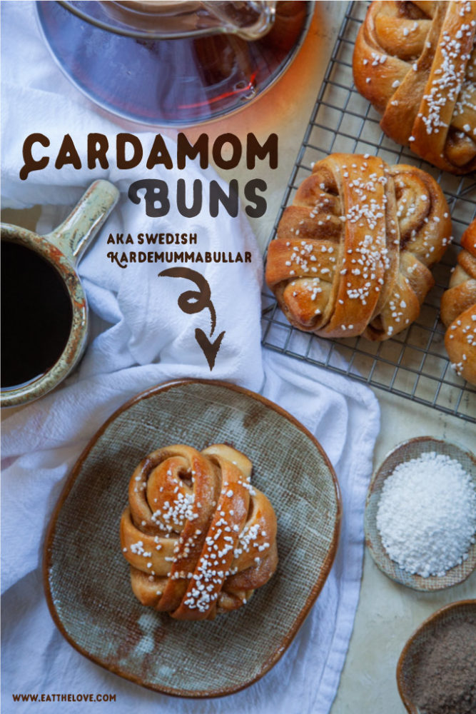 a cardamom bun on a plate with a cup of coffee and a chemex pot of coffee next to it. Beside the plate is a wire cooling rack with more cardamom buns and two small plates with Belgian pearl sugar and ground cardamom spice in them.