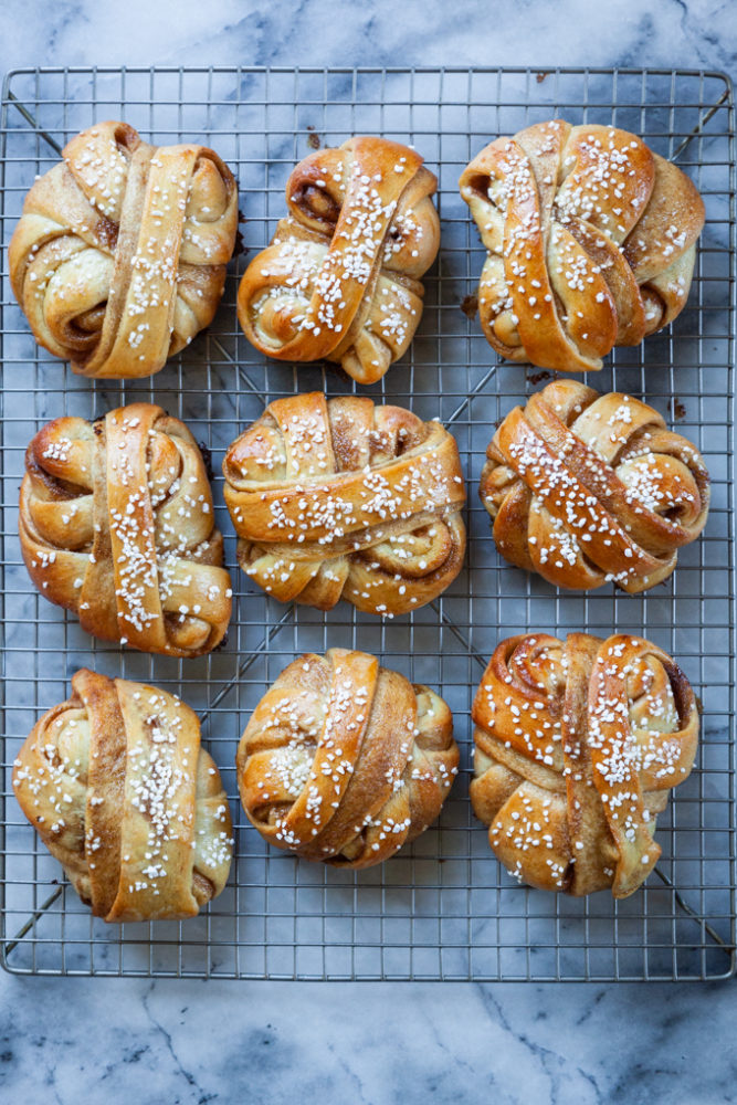 A wire cooling with cardamom buns on it.