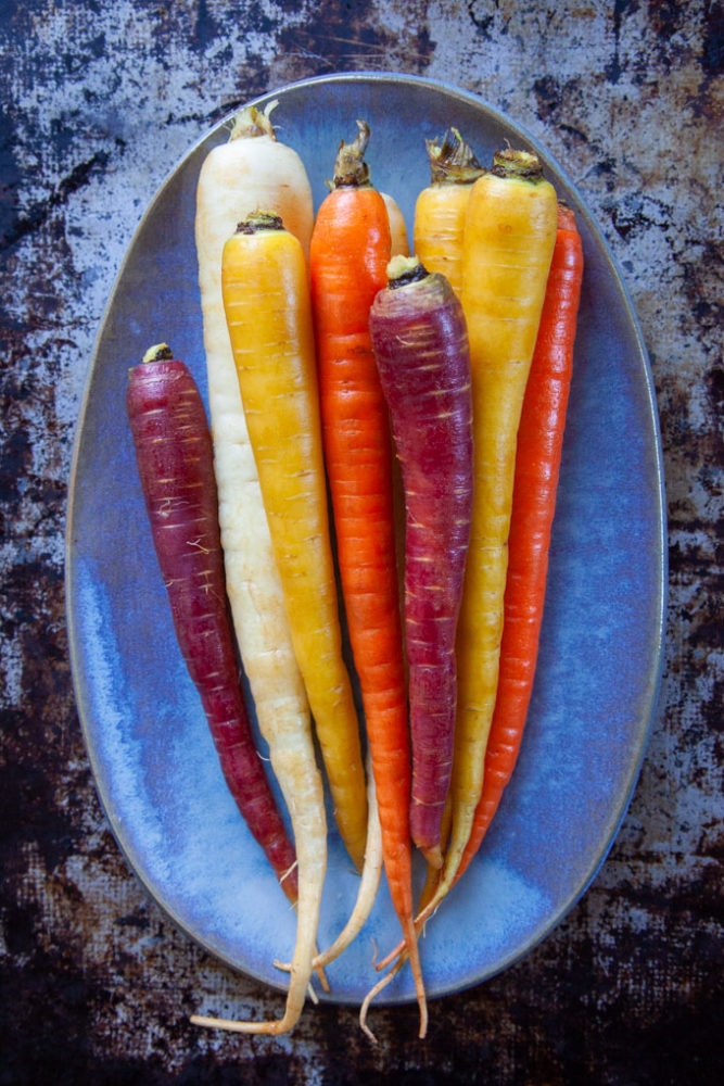 Rainbow carrots on a blue plate.