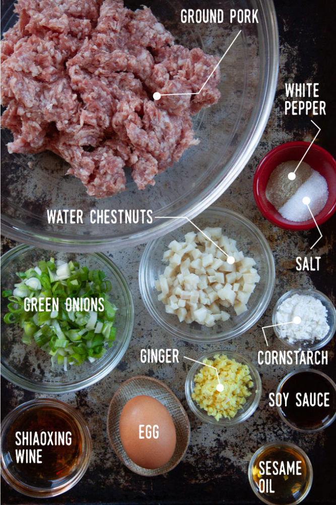 Ingredients for the pearl meatball filling in bowls, including ground pork, water chestnuts, white pepper, salt, cornstarch, an egg, green onions, ginger, soy sauce, shaoxing wine and sesame oil.