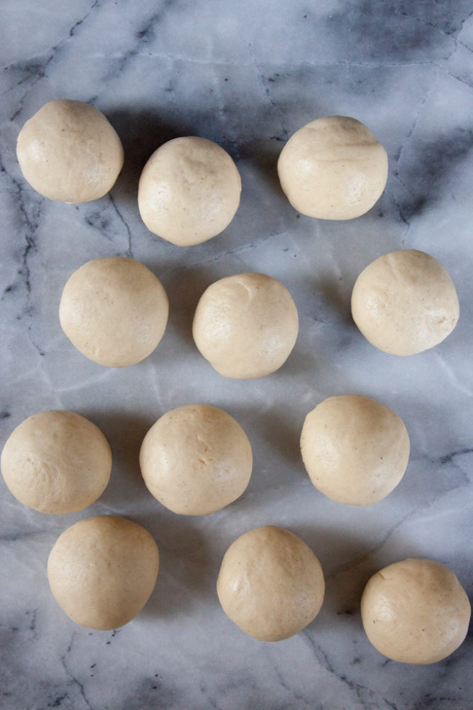 12 rounds dough balls on a marble surface.